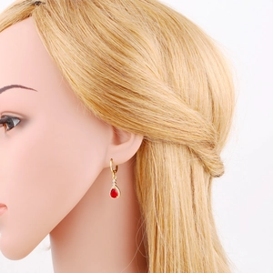 Detailed view of teardrop red zircon earrings on model with golden pear cut stones