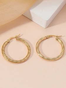 Close-up of golden twisted rope texture hoop earrings with elegant metal surface detail
