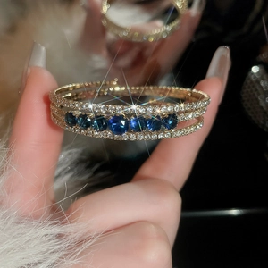 Macro detail of a triple-layered gold ring with blue sapphires and pavé diamonds