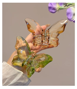 Detail of orange and green translucent butterfly hair claws with glossy amber finish