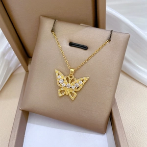 Detail shot of a hollow gold butterfly necklace pendant with pavé crystals on a soft pad