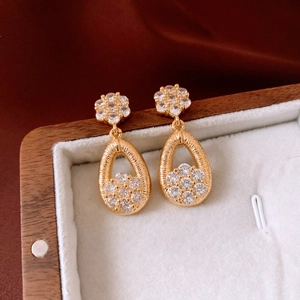 Macro view of 18K gold plated teardrop earring with flower design and sparkling zircons