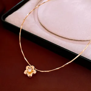 Gold plated flower pendant necklace with zircon on elegant snake chain over red velvet