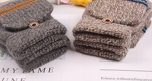 Detail of knitted winter gloves with flip top lid and vintage wood button decoration