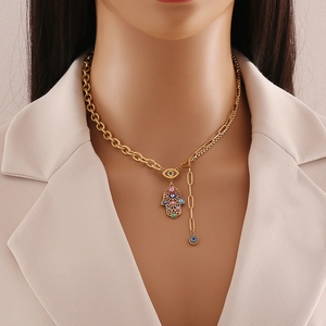 Gold Hamsa Hand and Evil Eye necklace on professional model wearing a beige blazer