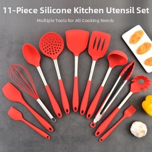 Eleven-piece red silicone kitchen utensil set with stainless steel handles on stone surface