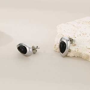 Détails macro des boucles d'oreilles en acier argenté avec pierres noires en goutte