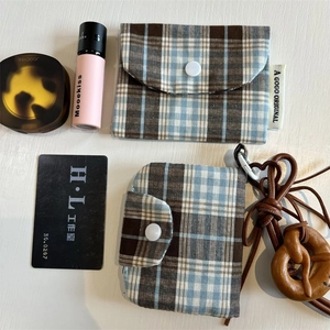 Detail of plaid fabric pouches with snap button closure and wooden pretzel pendant charm