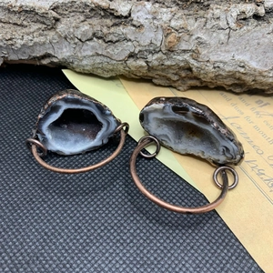Détail macro de pendentifs en géode d'agate naturelle avec bords en cuivre sur fond vintage