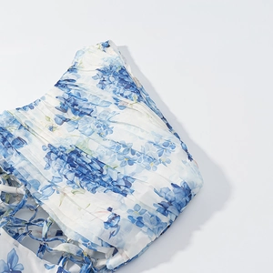 Detail of blue and white floral print dress featuring pleated fabric and cutout tie design