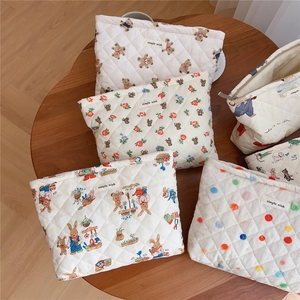 Quilted cotton cosmetic bags with cute bear and floral patterns on a wooden table