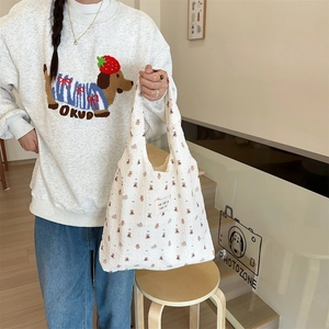 Detail of white seersucker tote bag featuring cute brown bear prints and a textile label