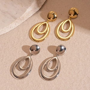Polished gold and silver multi-layer hollow oval drop earrings on stone prop