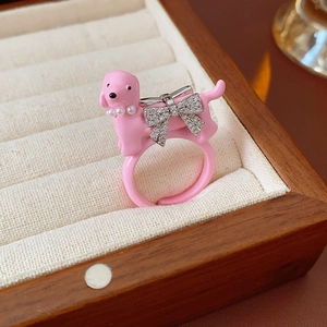 Detail of pink puppy ring with pearl collar and rhinestone bow in a wooden jewelry box