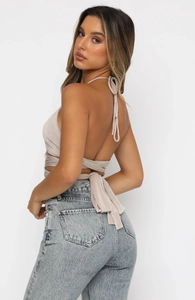 Détail d'un haut dos nu beige à licou avec tissu brillant et bretelles croisées
