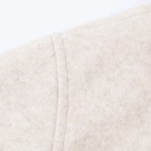 Close-up of beige wool coat fabric showing soft texture and premium stitching detail