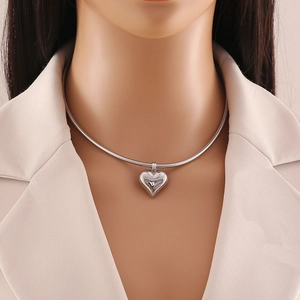 Minimalist heart pendant on silver snake chain necklace worn by professional model