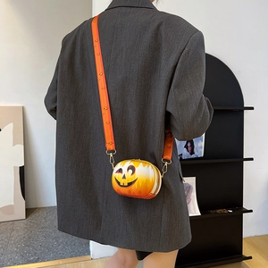 Detail of orange pumpkin crossbody bag with smiley face and wide graphic strap