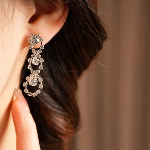Close-up of tassel earrings with shimmering crystals and intricate hollowed round patterns