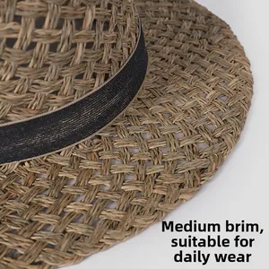 Detailed macro view of woven straw sun hat with textured black ribbon trim and flat brim