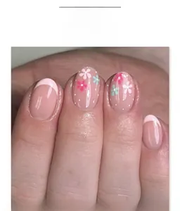 Detailed view of pink press-on nails with white French tips and delicate floral patterns