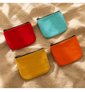 Flat lay of colorful canvas coin purses in red, teal, yellow, and orange with YKK zippers