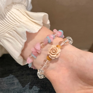 Detailed macro view of stacked aquamarine gemstone bracelets with a pink camellia flower