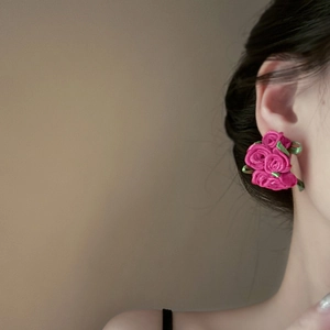 Close-up of a model wearing a rose-shaped fabric earring in elegant magenta pink