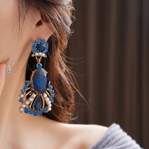 Detail view of vintage palace style earrings with blue gemstones and pearls on model