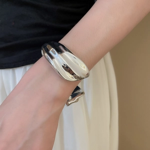 Macro shot of silver wide bone cuff bracelet with organic fluid design on female wrist