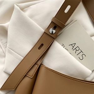 Detail of brown leather tote bag with silver buckle and adjustable shoulder strap