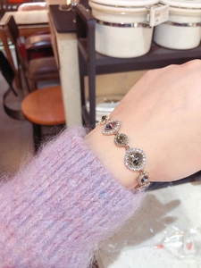 Close-up of rose gold bracelet featuring deep purple round gemstone and pavé diamonds