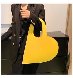 Close-up of heart-shaped yellow felt handbag featuring unique asymmetric art design