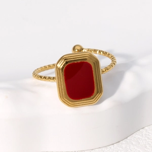 Vintage gold square ring with red enamel and twisted band on white marble texture