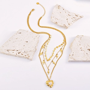 Three-layer gold necklace with lightning charms and a heart pearl pendant on white stones