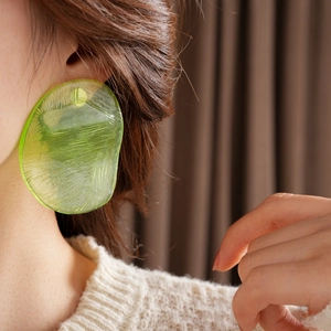 Close-up of a large green irregular resin earring with ice crack texture on model