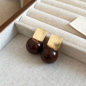 Macro shot of geometric resin earrings with brushed gold squares and brown balls