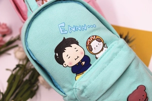 Close-up of light blue canvas pencil case featuring a cute cartoon dog and bear patch