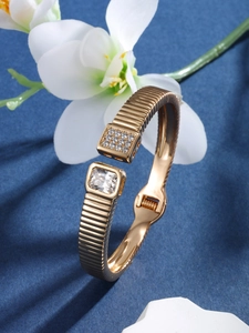 Macro detail of luxury gold-plated bangle with square zircon settings and textured metal