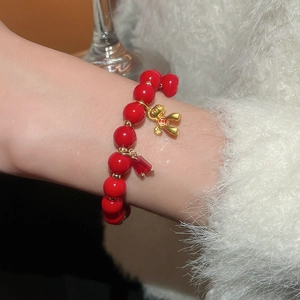 Close-up of red beaded bracelet featuring a gold Snoopy-style charm and faceted crystal