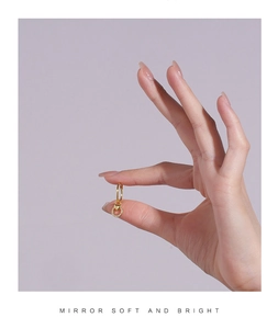 Detailed close-up of a gold heart drop earring with zircon held between fingertips