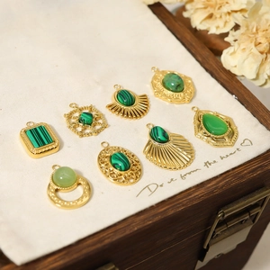 Detailed close-up of vintage gold-plated pendants with green natural stone on linen