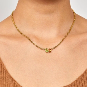Detail of gold chain necklace with green rectangle and orange oval zircon stones