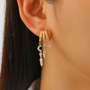 Macro shot of gold-plated hoop earrings set with zircons featuring moon and star charms