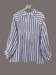 Detail of blue and white vertical striped shirt featuring decorative ruffle trim on shoulders