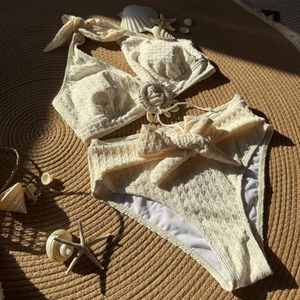 Detail of cream waffle bikini top with shell charms and high-waisted bow swim bottom