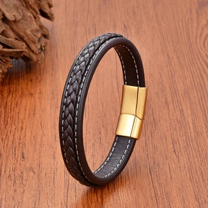 Detail of black woven leather bracelet with gold magnetic clasp on a wooden background