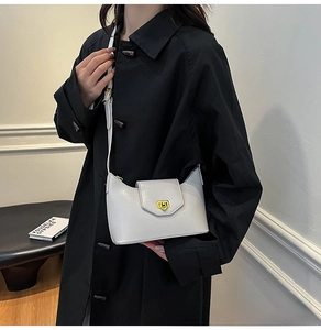 Close-up of light gray crossbody bag with gold twist lock on black coat lifestyle setting