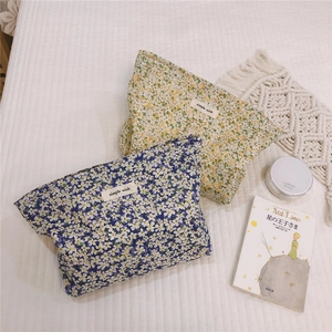 Detailed view of floral cotton makeup pouches on a white bed with aesthetic props