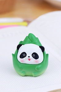 Close-up of cute panda figurine wrapped in green bamboo shoots for office desk decor